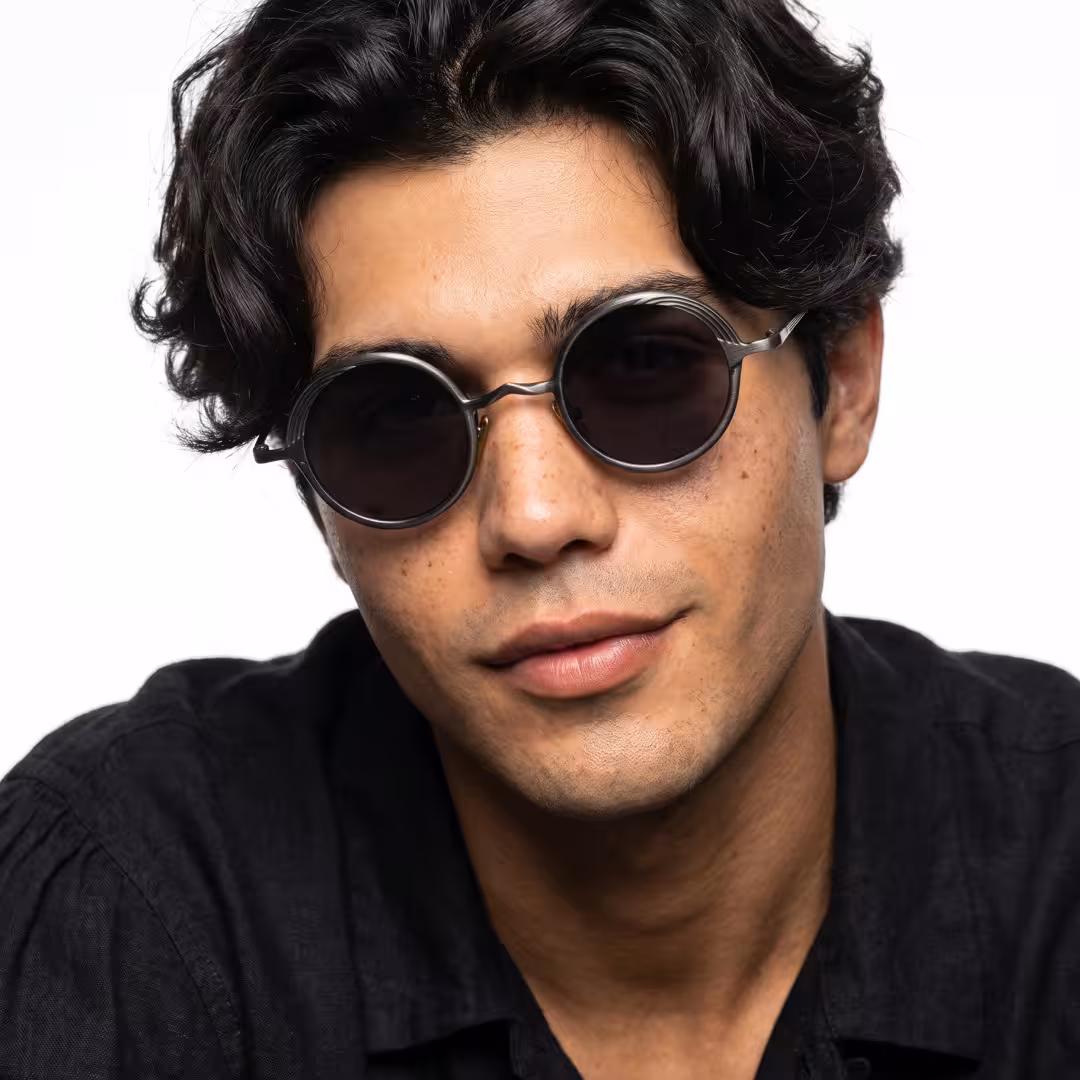 Front view of male wearing john lennon black round sunglasses, tilting head, confident expression, RM0402601