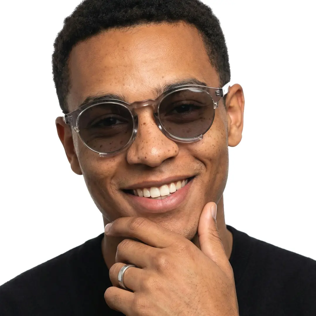 Front view of male wearing grey round sunglasses, resting chin on hand, soft smile, RR0062402