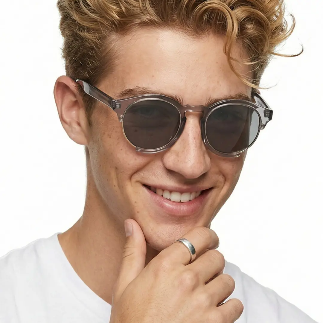 Three-quarter view of male wearing grey round sunglasses, resting chin on hand, friendly smile, RR0062402