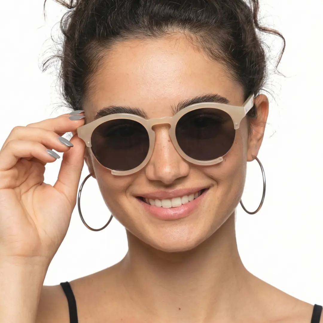 Front view of female wearing pink round sunglasses, holding glasses, soft smile, RR0062402