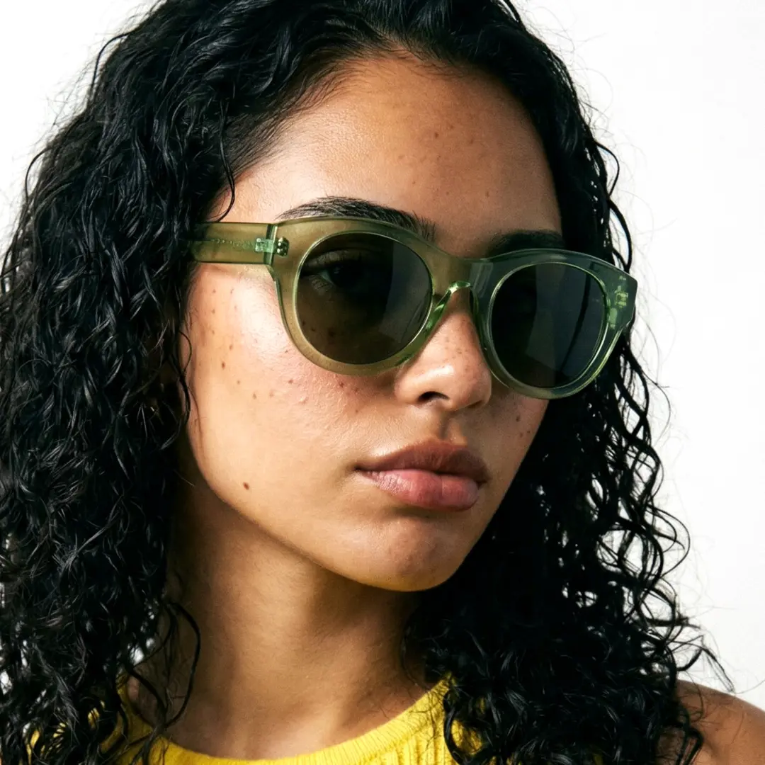 Profile view of female wearing green round sunglasses, neutral expression, RR0242302