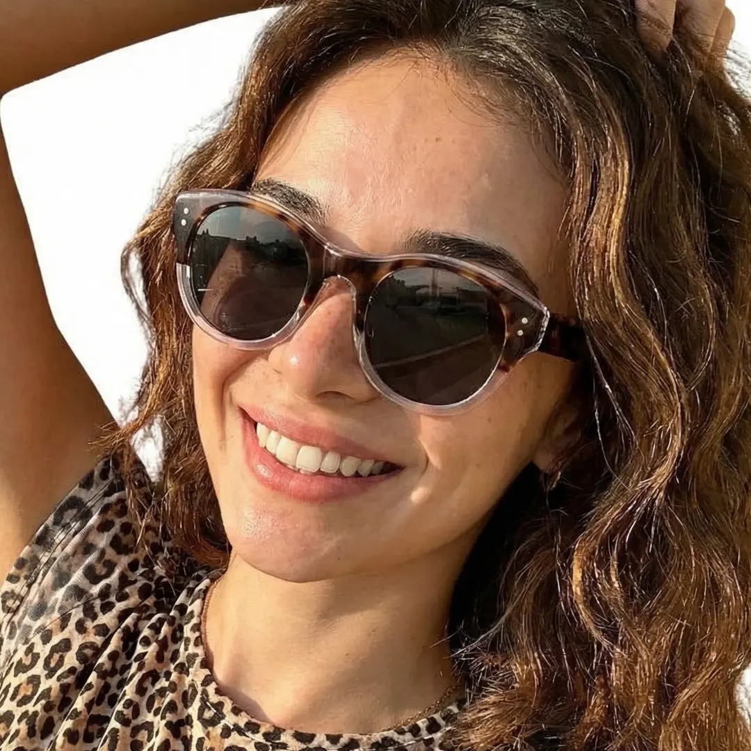 Tilted head view of female wearing tortoise round sunglasses, natural smile, RR0242302