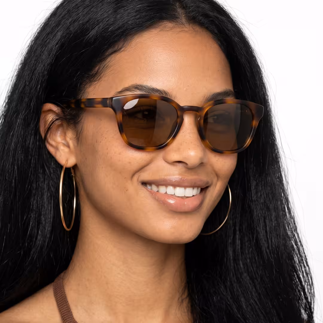 Three-quarter view of female wearing tortoise square sunglasses, smiling, SP0032404