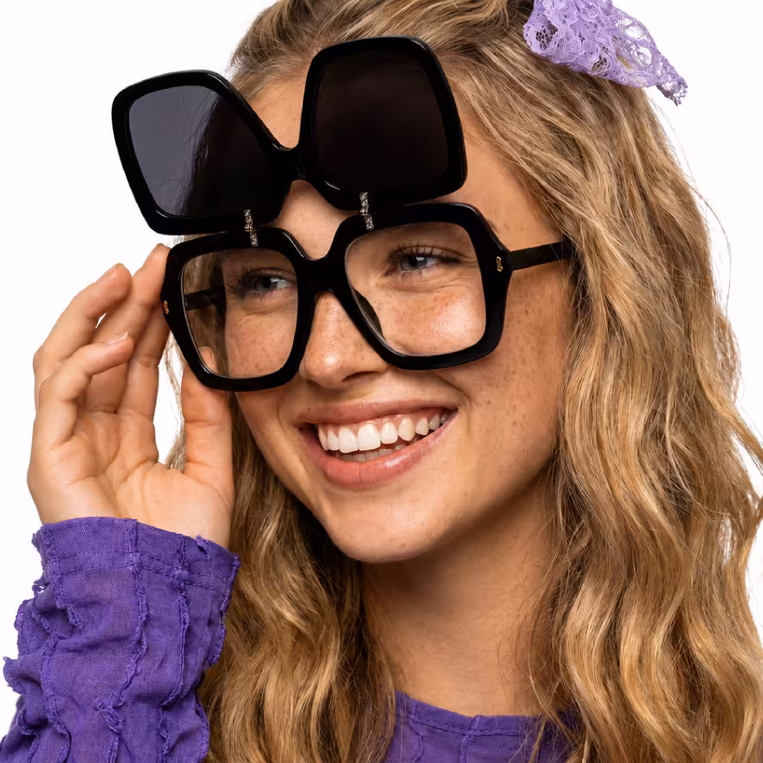 Close-up view of female wearing vintage black square flip-up eyeglasses, touching frame, smiling, SP0192603