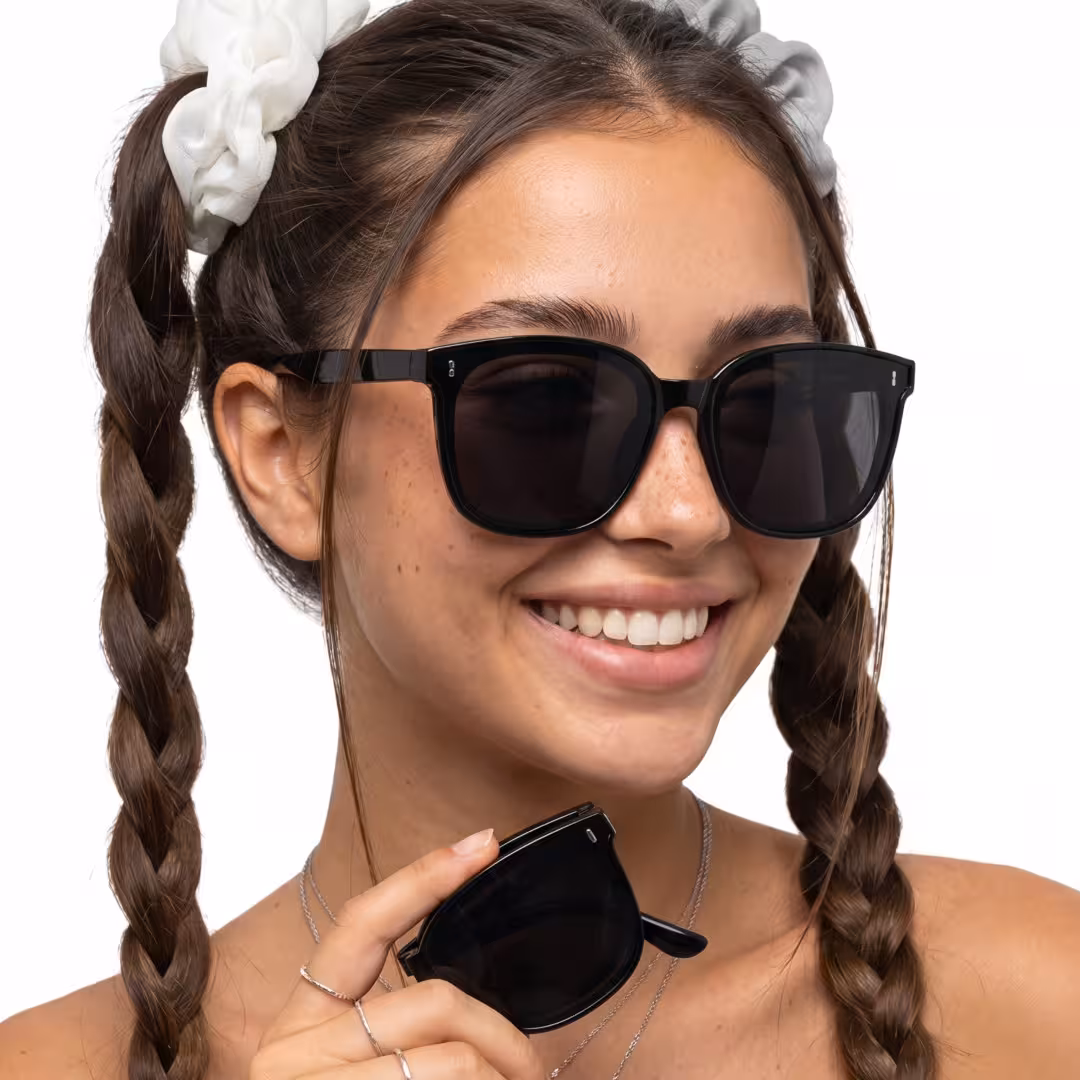 Front view of female wearing black square sunglasses, holding glasses, smiling, SP0302604