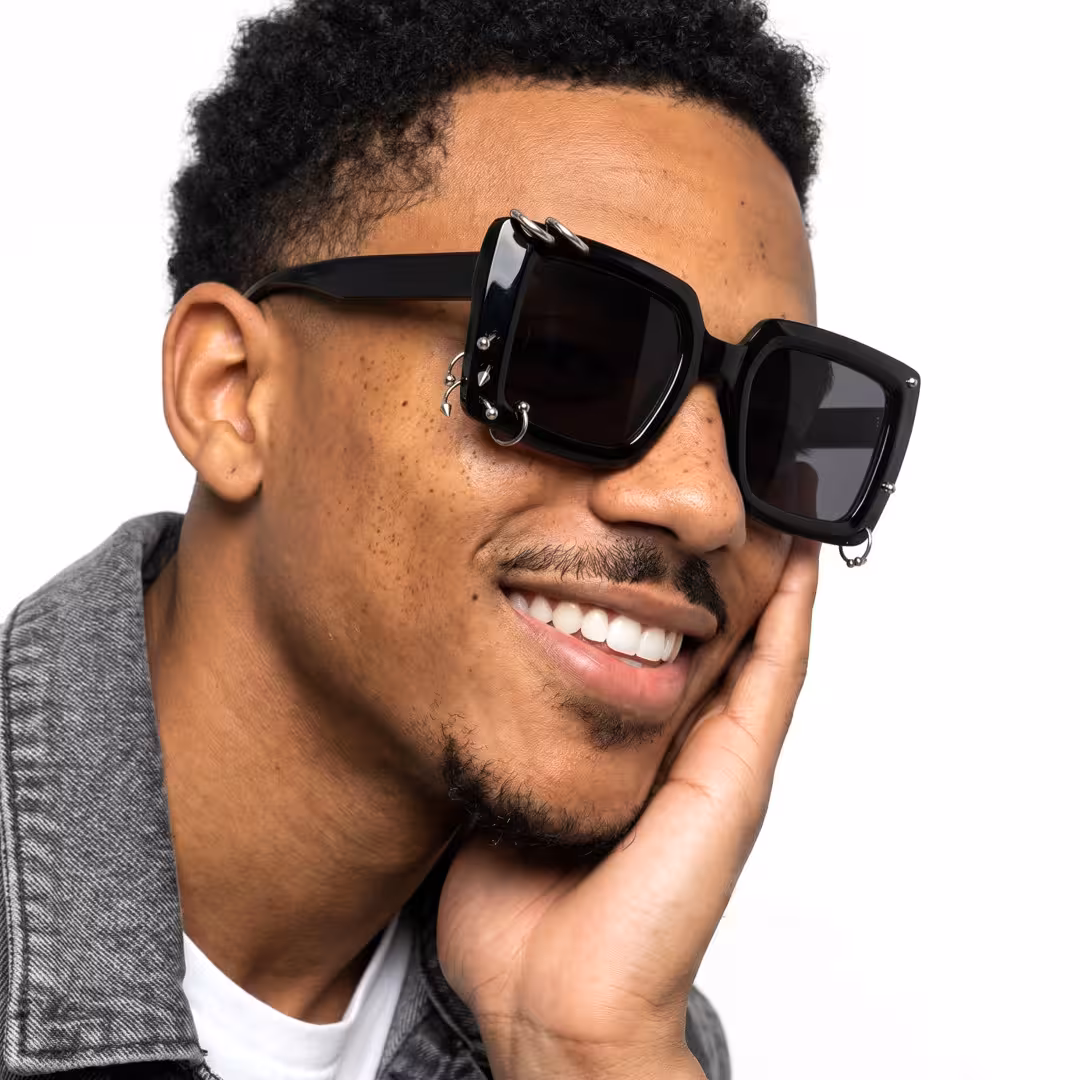 Profile view of male wearing black square sunglasses, resting chin on hand, smiling, SR0052509