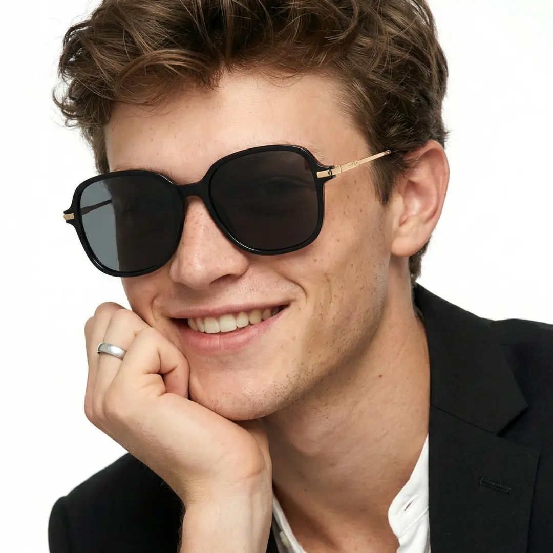 Front view of male wearing black square sunglasses, resting chin on hand, smiling, SR0222410