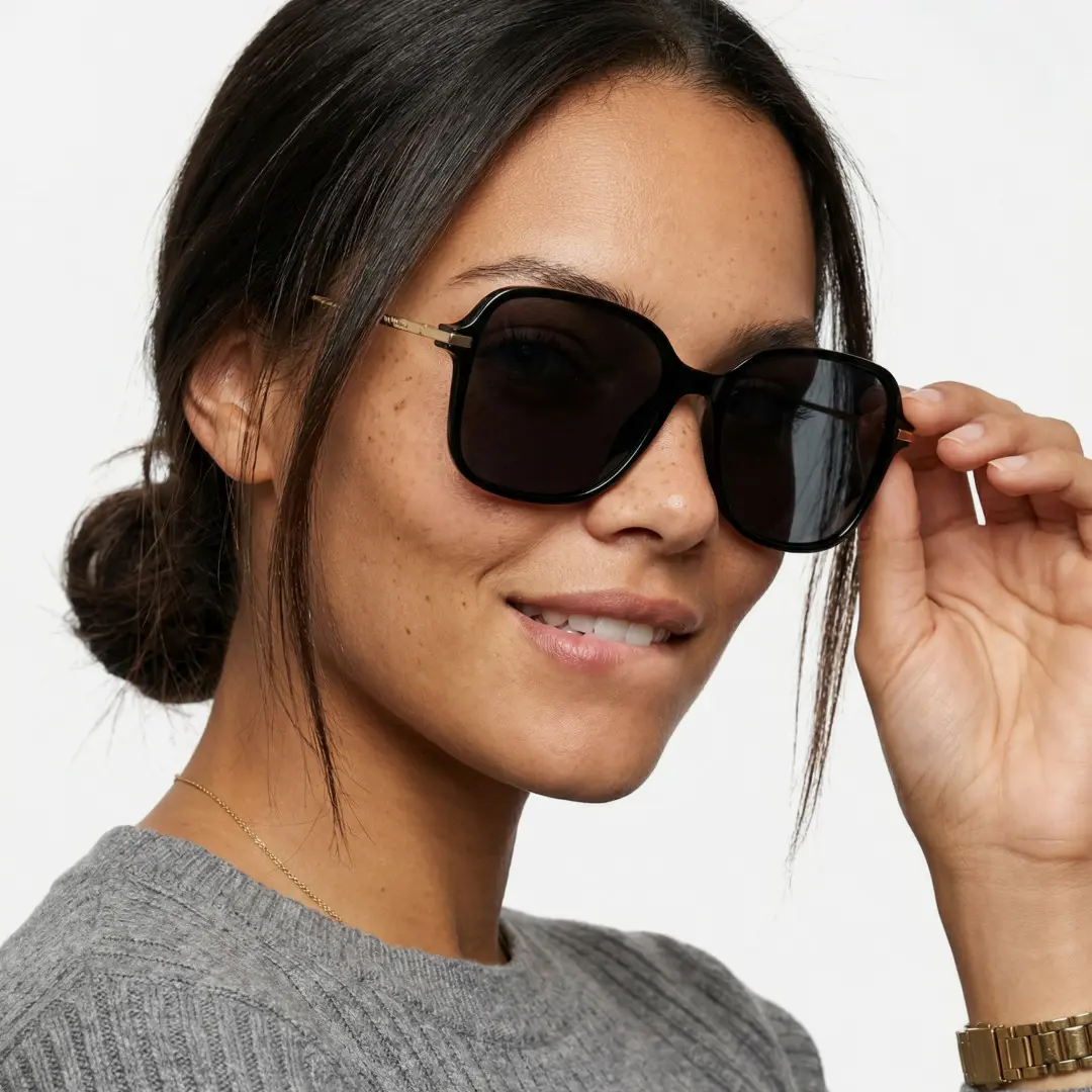 Three-quarter view of female wearing black square sunglasses, touching frame, friendly smile, SR0222410