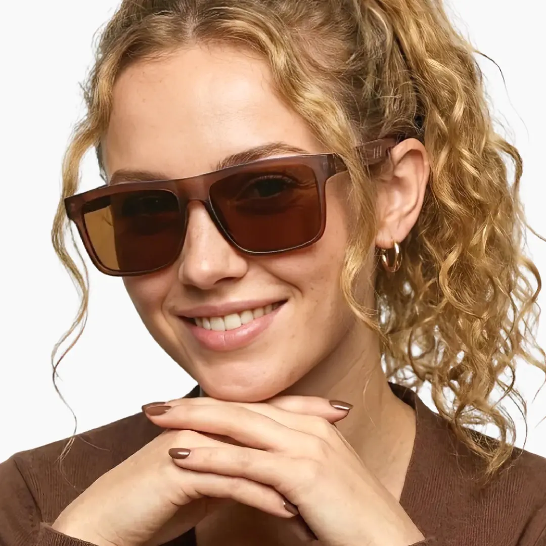 Front view of female wearing brown square sunglasses, resting chin on hand, smiling, SX0012304