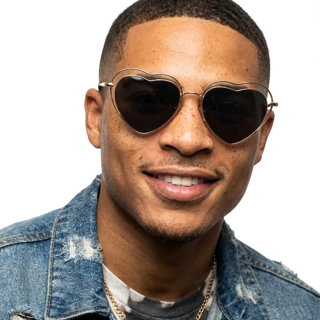 Tilted head view of male wearing black heart sunglasses, smiling, UM0082506