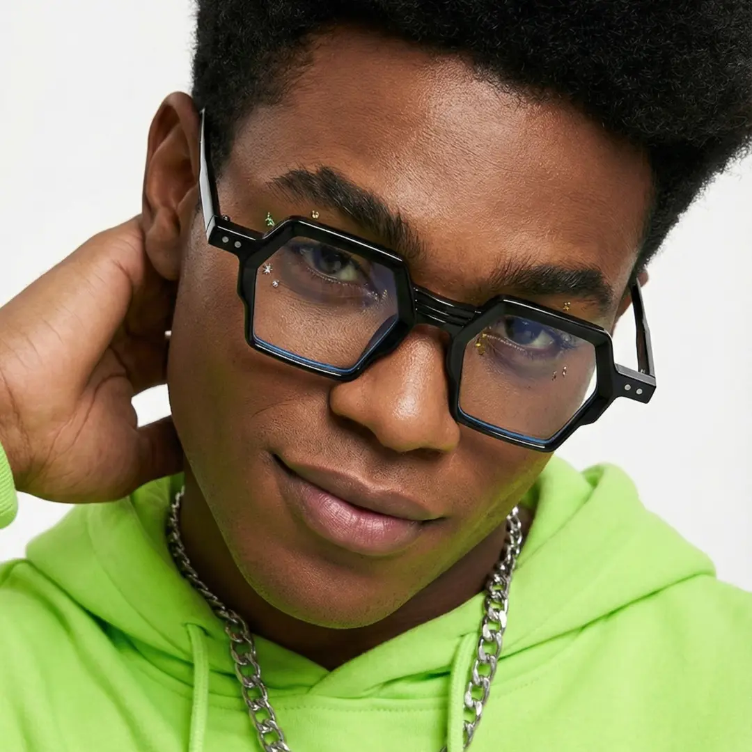 Front view of male wearing fashion black geometric eyeglasses, hand in hair, relaxed expression, GA0132302