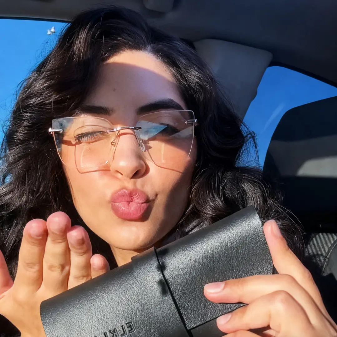 Close-up view of female wearing pink cat eye eyeglasses, winking, blowing a kiss, CX0082507