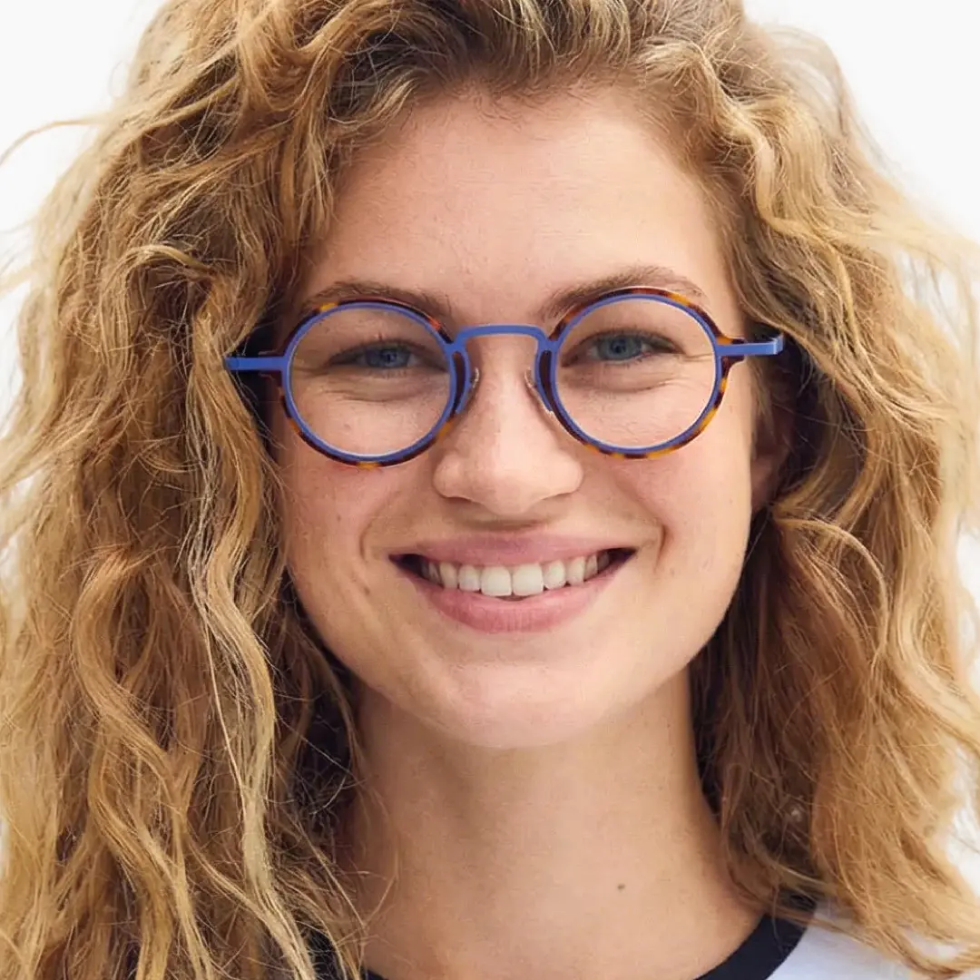 Straight-on view of female wearing blue tortoise round eyeglasses, smiling, RA0302402